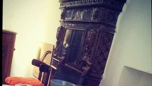 Una mesa de comedor dispuesta con fuentes, platos y cubiertos, con una vela y una silla al fondo.