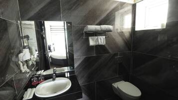Un baño moderno con un espejo grande, un lavamanos blanco, un inodoro y un perchero para toallas.