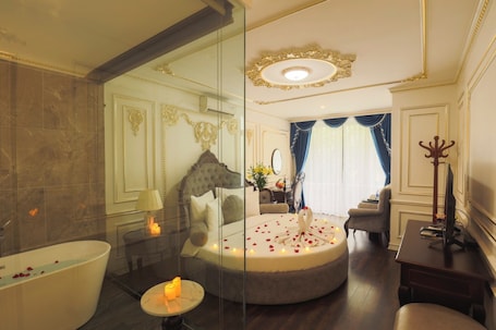 A luxurious bathroom with a bathtub, a round seating area with rose petals, and a mirror.
