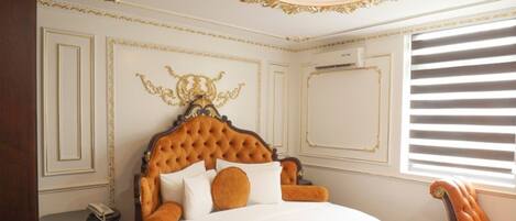 A luxurious bedroom with a tufted headboard, a round bed, a wooden bench, and a chair.