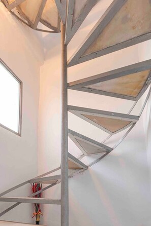 Stunning spiral staircase ascends within a spacious room with a window.
