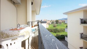 A balcony with a table and chairs, overlooking a residential area with houses and greenery. - 1 bedroom beautiful apartment in Parco dei Tigli (Parco dei Tigli)