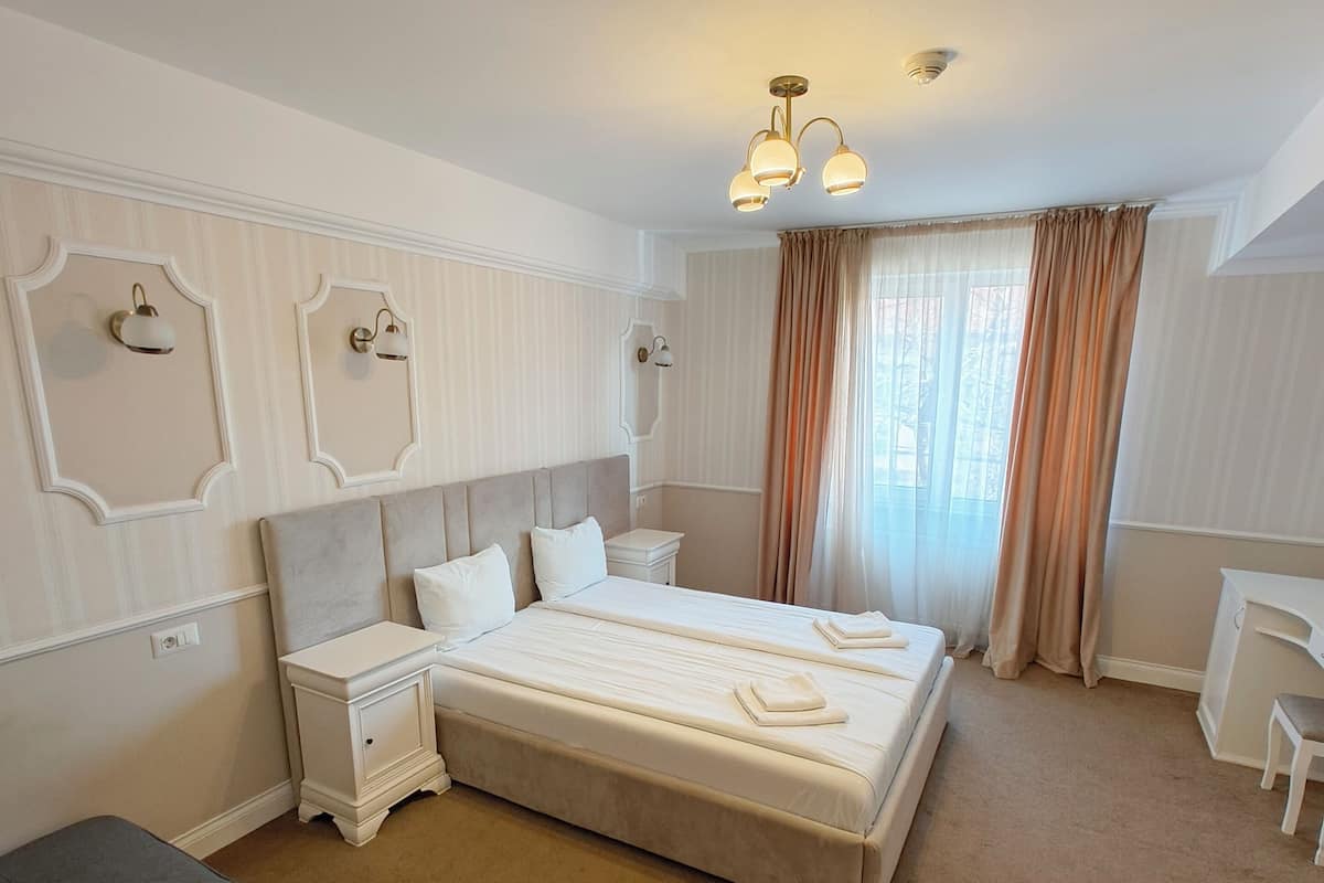 A bedroom with a large bed, bedside tables, a desk, and a chair.