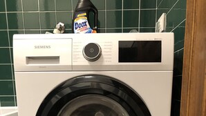 A front-loading Siemens washing machine in a bathroom with green tiles.