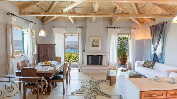 Una habitación con una mesa de comedor, sillas, un sofá, chimenea y un tapete con forma de estrella de mar.