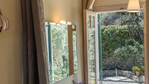 Un baño con un lavamanos grande, un espejo y vistas a una piscina y jardín a través de una puerta abierta.