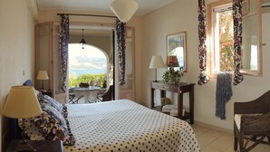 Un dormitorio con cama, una silla, una mesa y vistas al exterior.