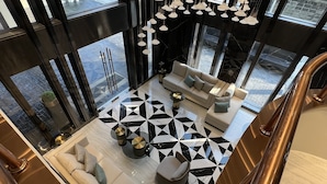 A modern interior with a geometric patterned floor, a sofa set, and hanging pendant lights. - ARNI Skye Hotel (Bangkok)