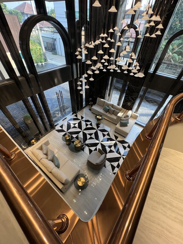 A modern interior with a geometric patterned floor, a sofa set, and hanging pendant lights. - ARNI Skye Hotel (Bangkok)