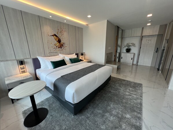 Un dormitorio moderno con una cama grande, una mesita de noche, una mesa redonda y una obra de arte colgada en la pared.