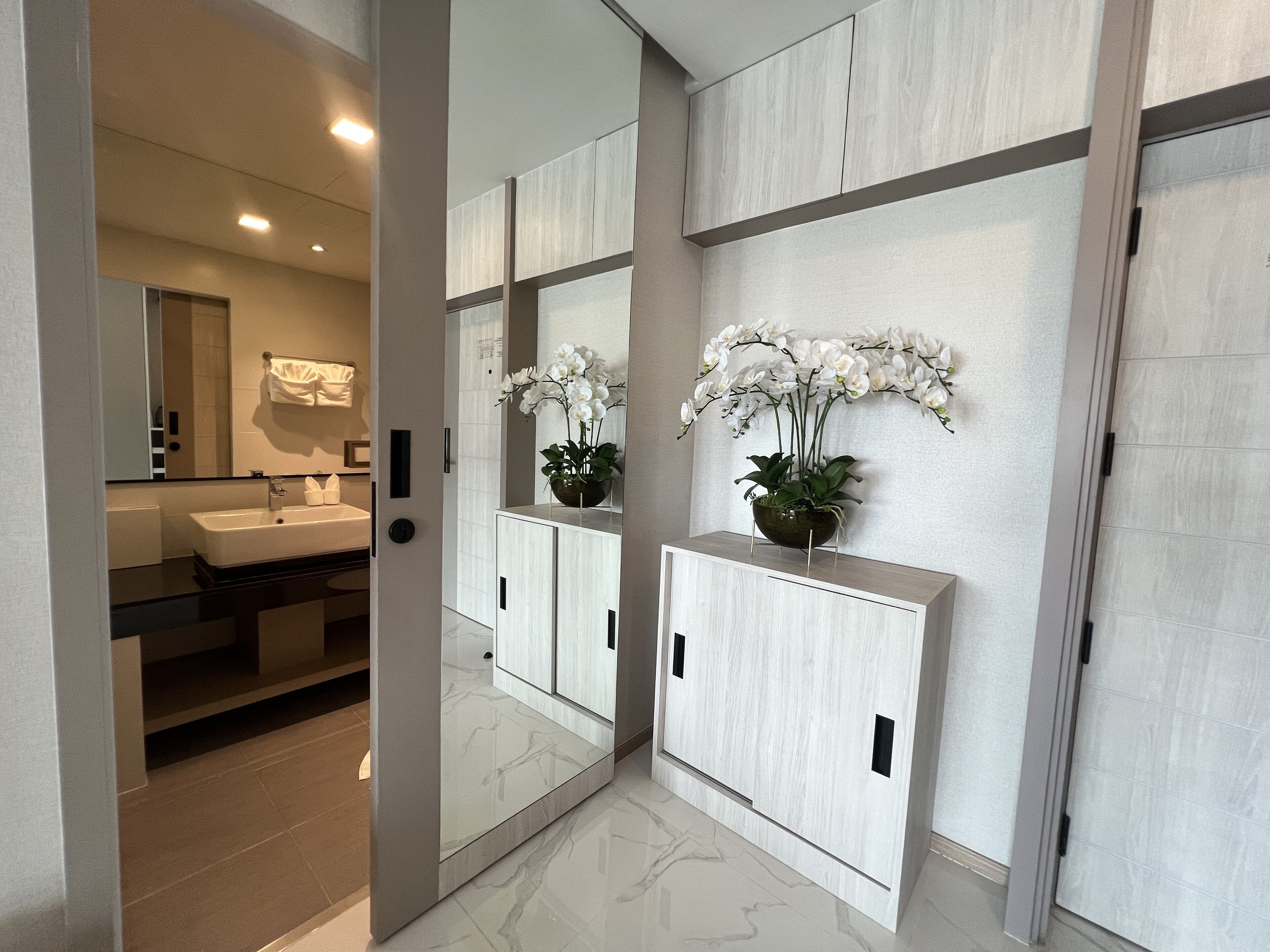 A modern bathroom with a large mirror, a sink, and a vanity with cabinets.