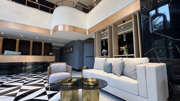 A modern lobby with a geometric patterned floor, a white sofa, and a reception desk. - ARNI Skye Hotel (Bangkok)