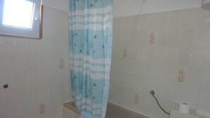 A bathroom with a bathtub, a shower curtain, and a toilet.