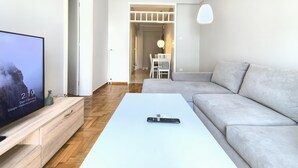 A modern living room with a flat-screen TV, a white coffee table, and a grey sofa. - Dionysos - Acropolis Residence Apartment (Athens)