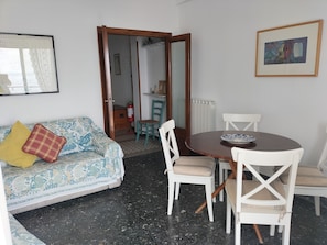 Un salon comprenant un canapé, une table à manger avec des chaises, un extincteur et un radiateur.