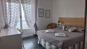 Une chambre à coucher avec un lit, une chaise, un bureau et une fenêtre avec des rideaux.