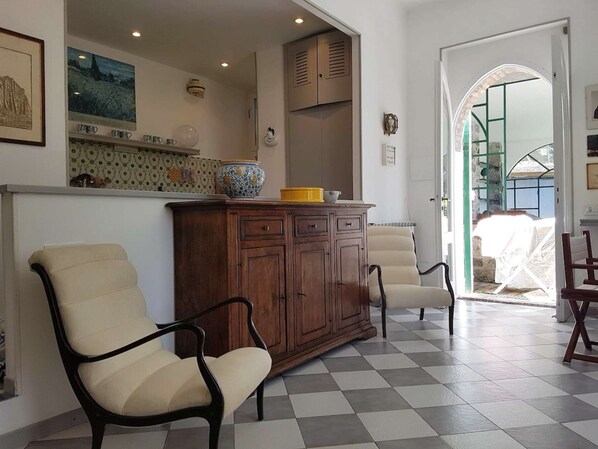 A living room with a checkered floor, two beige armchairs, a wooden cabinet, and a door leading to an outdoor area. - Benedetta Beautiful House - By the Sea with A/C (Levanto)