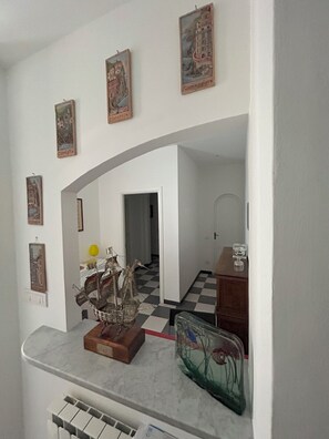 Une pièce avec un sol à carreaux, un comptoir en marbre et plusieurs tableaux encadrés accrochés au mur.