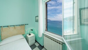 A room with a bed, a nightstand, a window with a view of the sea, and a radiator. - Bouganville House in the center - amazing sea view (Monterosso al Mare)