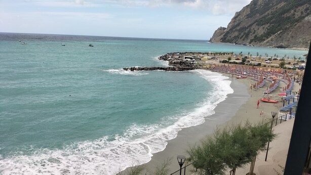 A beach with a rocky breakwater, a sandy shore, and a clear view of the sea. - Bouganville House in the center - amazing sea view (Monterosso al Mare)