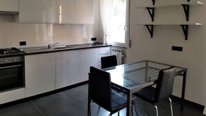 A modern kitchen with white cabinets, a gas stove, a sink, and a glass dining table with chairs.