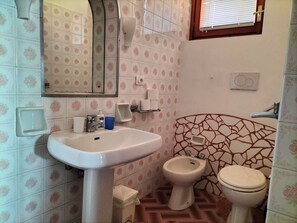 A bathroom with a sink, bidet, toilet, and a mirror.