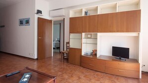 A room with a wooden cabinet, a television on a stand, and a chair.