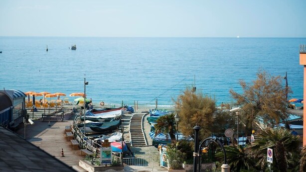 A coastal view with a pier, boats, and beach umbrellas.