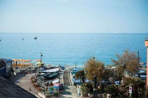 A coastal view with a pier, boats, and beach umbrellas.