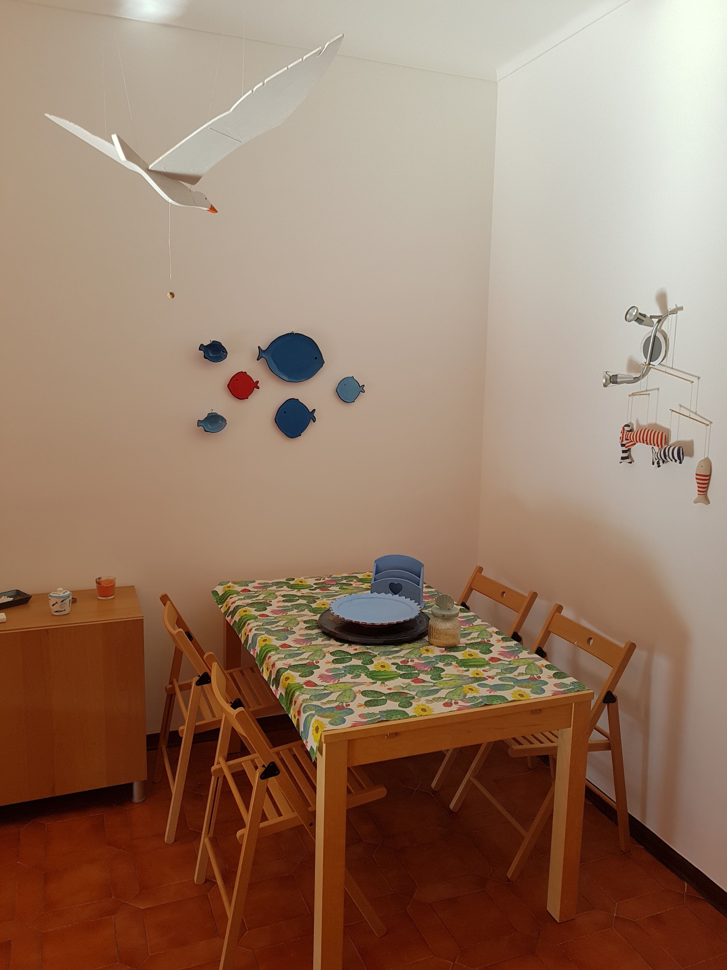 Ein Essbereich mit einem Holztisch, Stühlen und einer bunten Tischdecke.