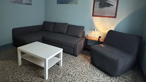 A living room with a grey sofa, a white coffee table, and a grey armchair. There are three framed pictures on the wall. - Delfino Cosy Apartment With A/C  Near best bea... (Monterosso al Mare)