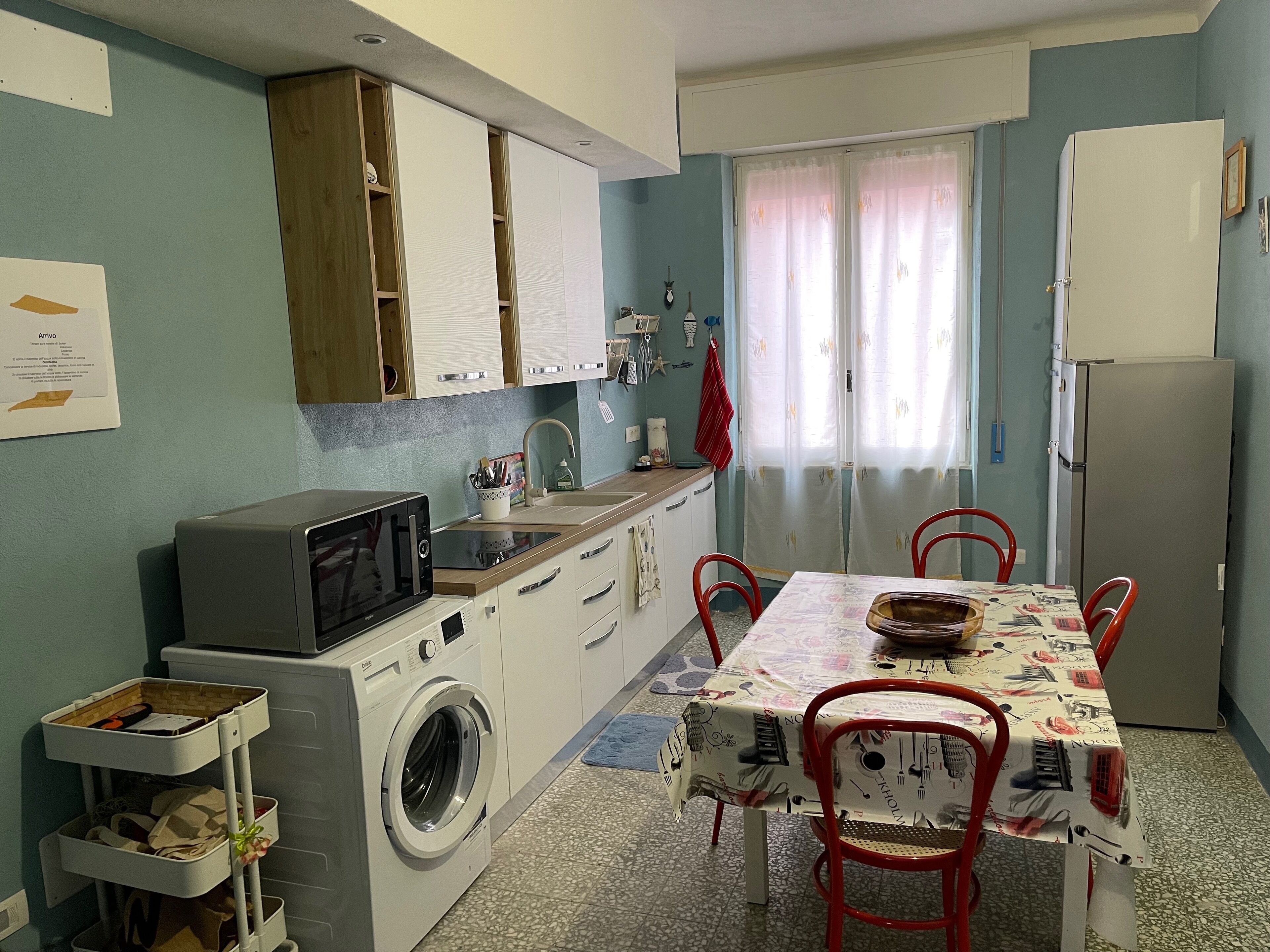 Een koelkast, een kookplaat, kookgerei, borden en bestek, een eettafel