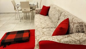 A living room with a red sofa, a patterned armchair, and a dining area with a table and chairs. - Eulalia Apartment- in the center near best bea... (Monterosso al Mare)