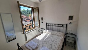 A bedroom with a bed, a window with a view of buildings, a radiator, and a small bedside table. - Eulalia Apartment- in the center near best bea... (Monterosso al Mare)