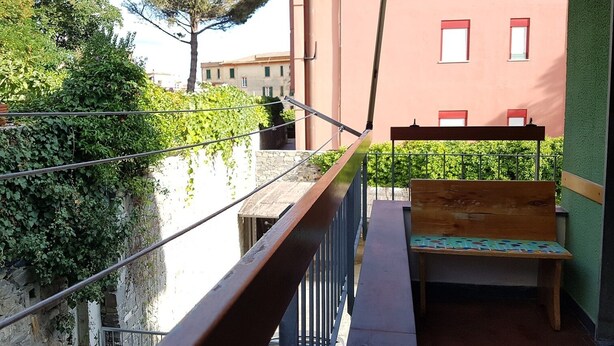 A balcony with a wooden bench, a metal railing, and a view of a building with windows and a tree. - Giuliana Cosy Apt central & near the best beaches (Monterosso al Mare)