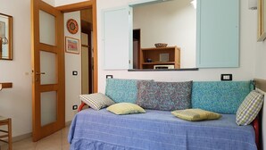 A bedroom with a bed, a wooden door, a mirror, and a shelf with a basket. - Giuliana Cosy Apt central & near the best beaches (Monterosso al Mare)