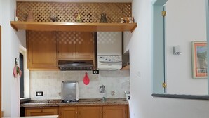 A compact kitchen with wooden cabinets, a gas stove, and a built-in oven. - Giuliana Cosy Apt central & near the best beaches (Monterosso al Mare)