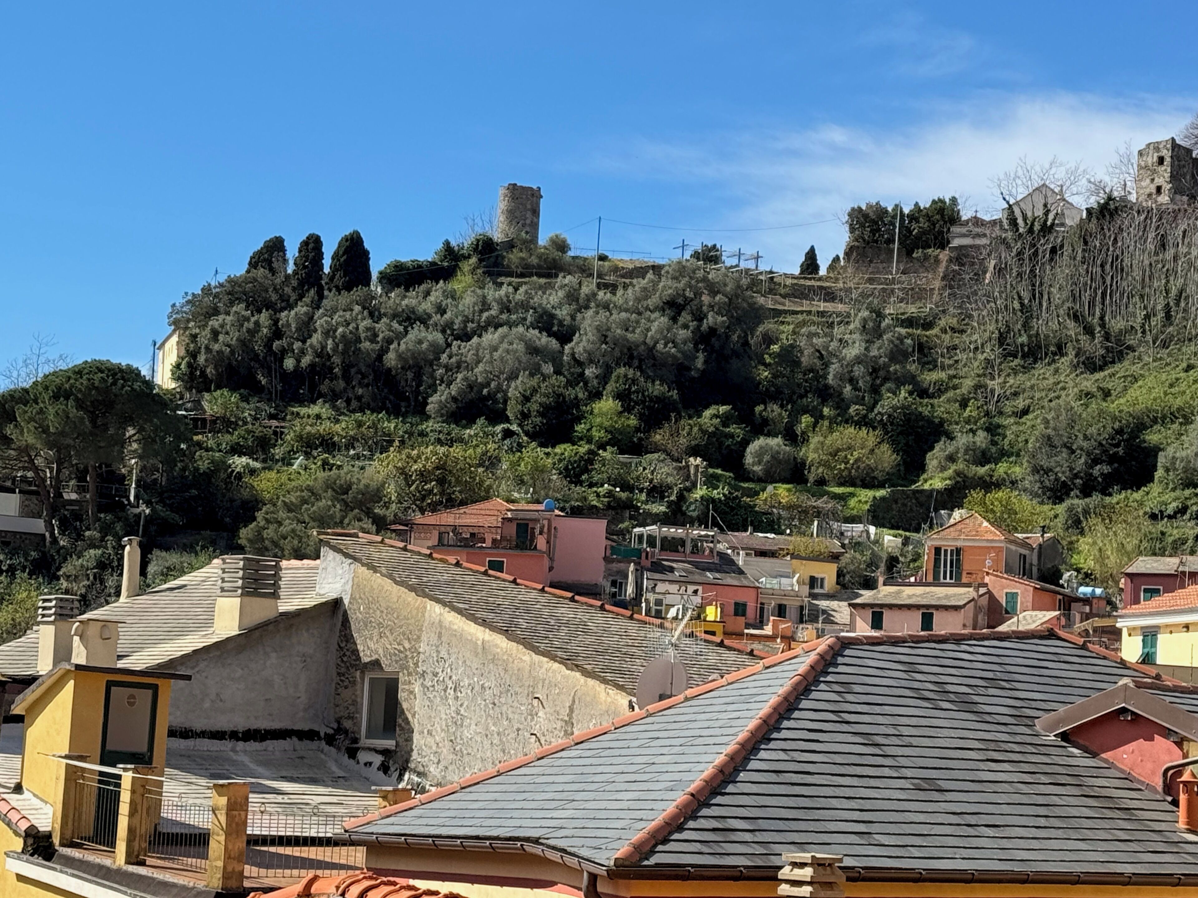 A hillside town with traditional architecture, including stone buildings and a prominent tower.