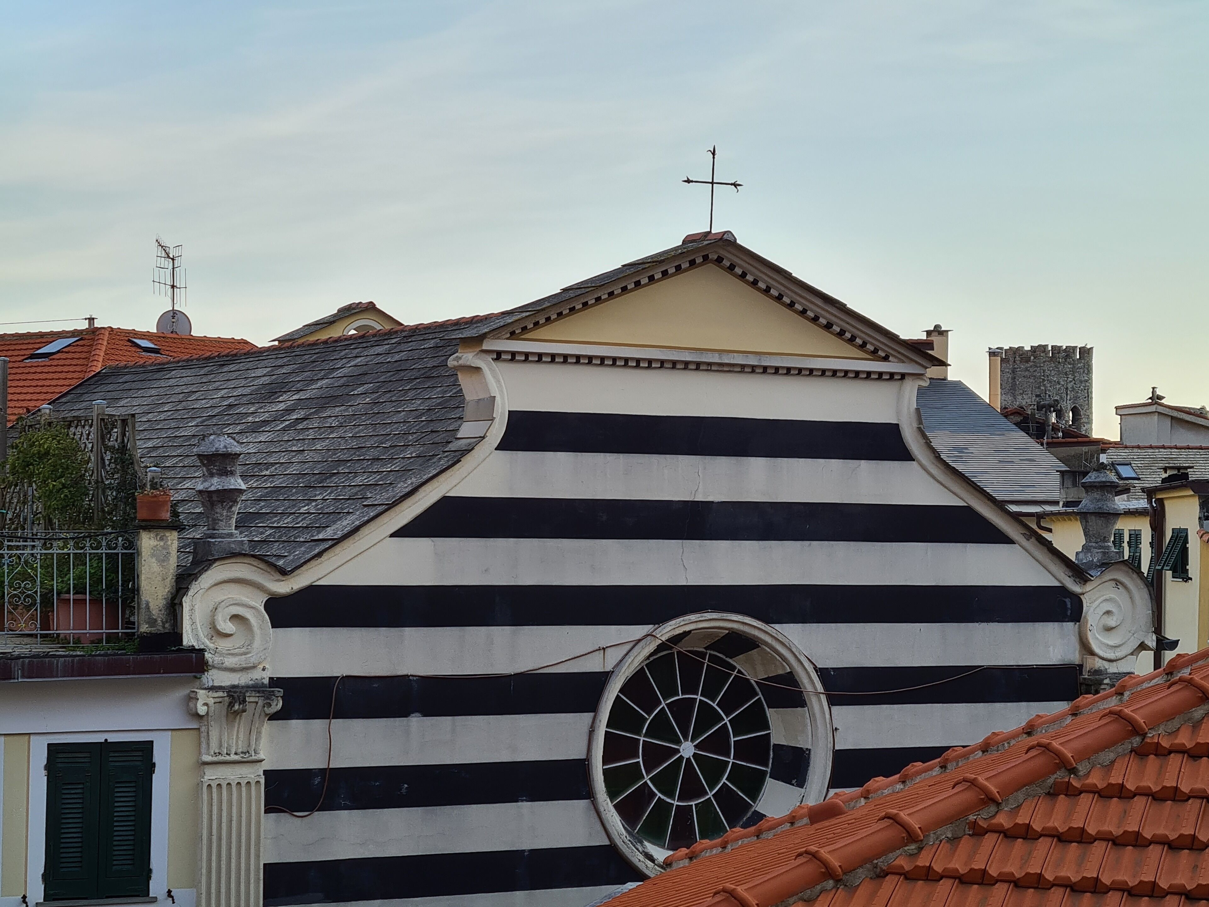 A building with a striped facade, a large circular window, and a cross on the roof.