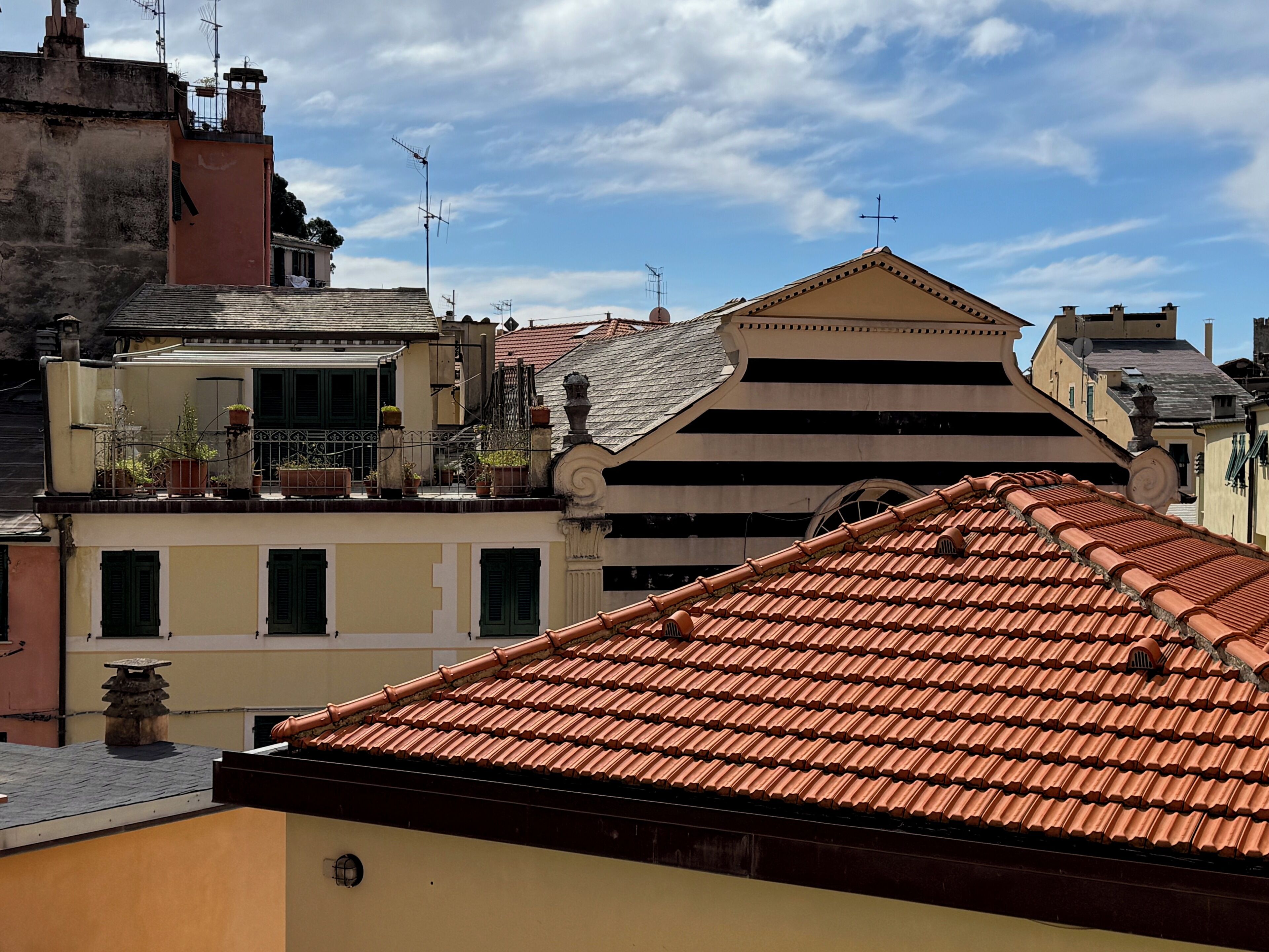 A building with a triangular roof and a balcony with potted plants.