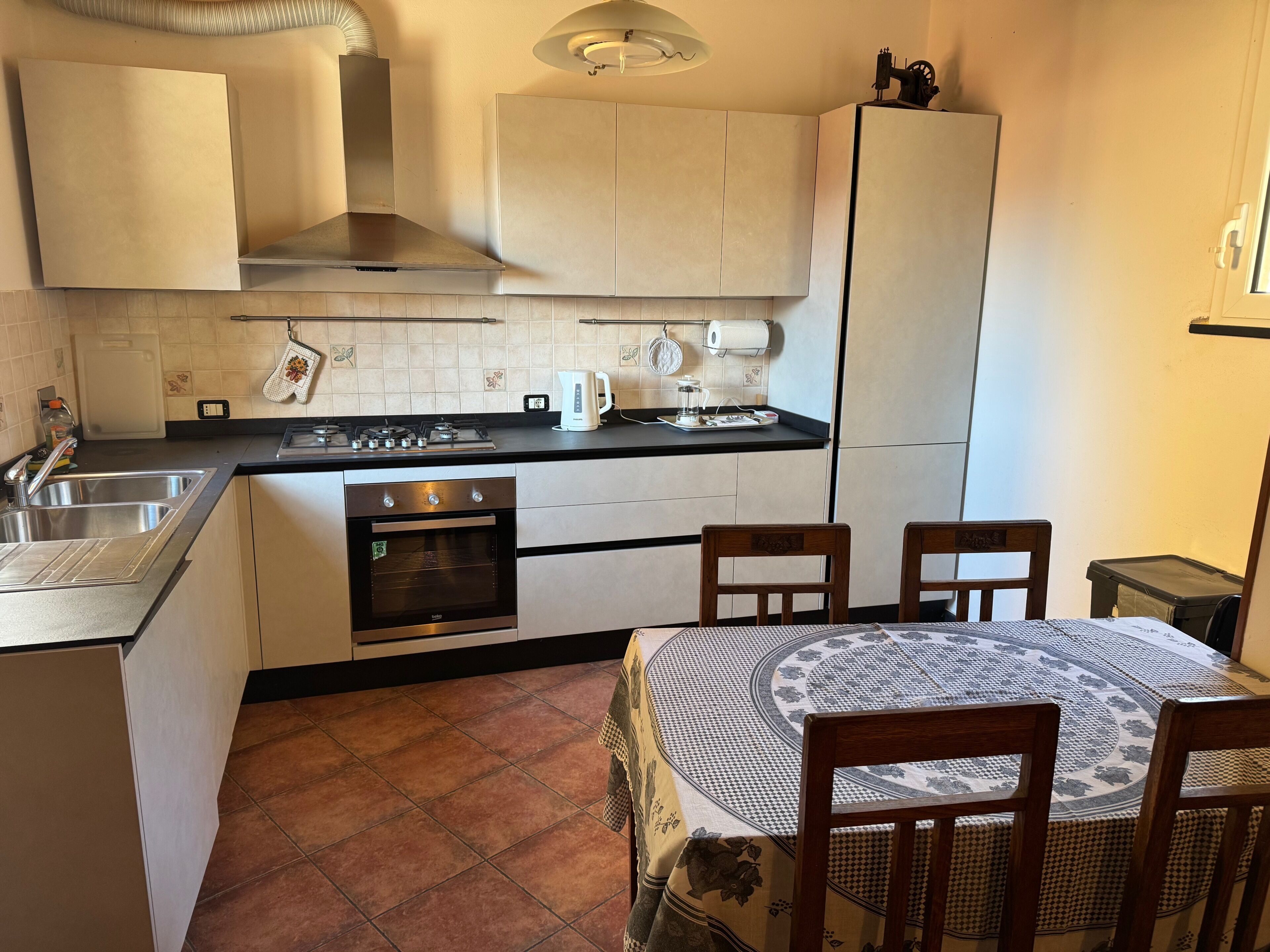 Una cocina con estufa, horno, fregadero y una mesa de comedor con sillas.