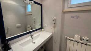 Ein Badezimmer mit Waschbecken, Spiegel, Fön, Handtrockner und Heizkörper.