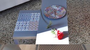 Una mesa con mantel estampado, un plato decorativo y una rosa roja.