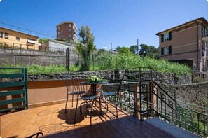 A terrace with a table and chairs, a stone wall, and buildings in the background. - Mary Bridge apartment in villa near best beaches (Monterosso al Mare)