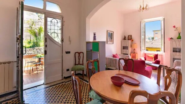 Comedor con mesa redonda y sillas, una estantería y vistas al exterior.
