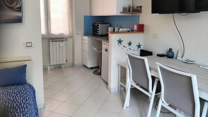 Une cuisine compacte avec des meubles blancs, un four à micro-ondes et un coin repas comprenant une table et des chaises.