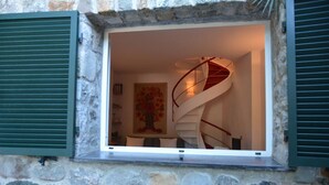 Una escalera de caracol en una habitación con paredes de piedra y un cuadro en la pared.