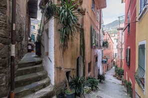 Una calle estrecha con escalones de piedra que conducen a un edificio con balcones y macetas.