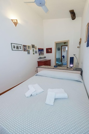 A bedroom with a bed, a desk, a mirror, and wall-mounted lights.