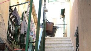 A narrow stairway with a green metal railing, leading to a landing.